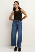 Woman wearing blue jeans and a black tank top against a white background