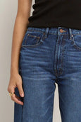 Close-up of blue jeans worn by a person against a neutral background