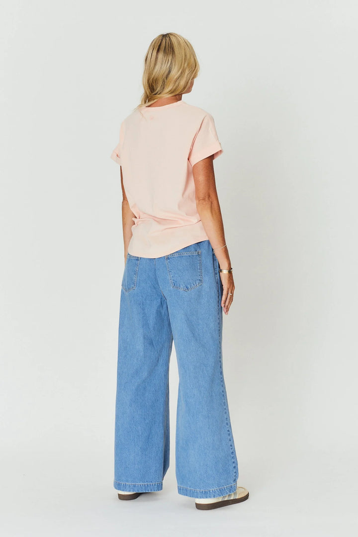 Woman wearing a light pink top and blue jeans on a white background