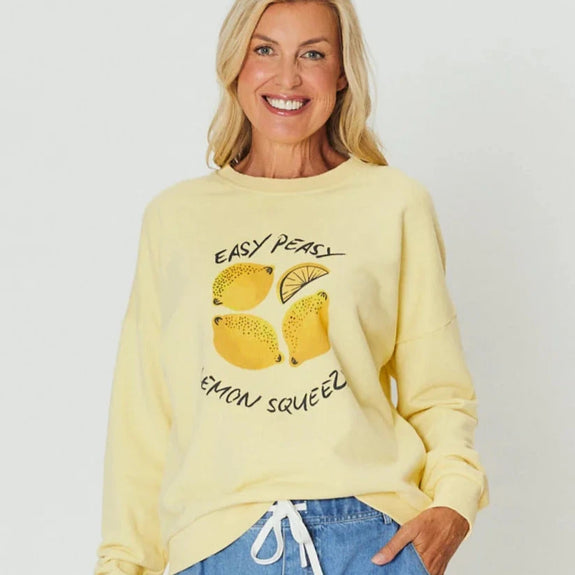 Woman wearing a yellow sweater with lemon design and text on a plain background