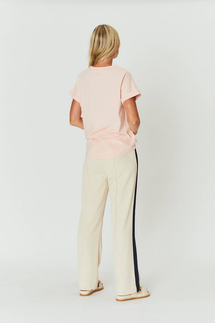 Person wearing a light pink top and beige pants with a black stripe on a white background