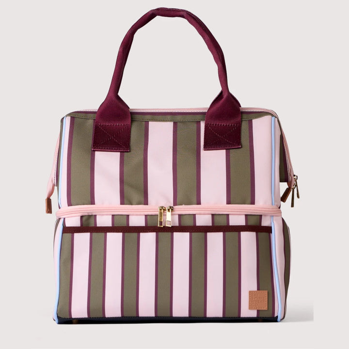 A striped diaper bag with vertical pink, olive green, and burgundy stripes, featuring a top zipper, a front zip pocket, and burgundy shoulder straps, shown against a light gray background.