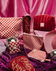 Red and white checkered pouches and decorative items on a pink and purple fabric background