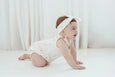 Baby in a white outfit with a headband on a white background