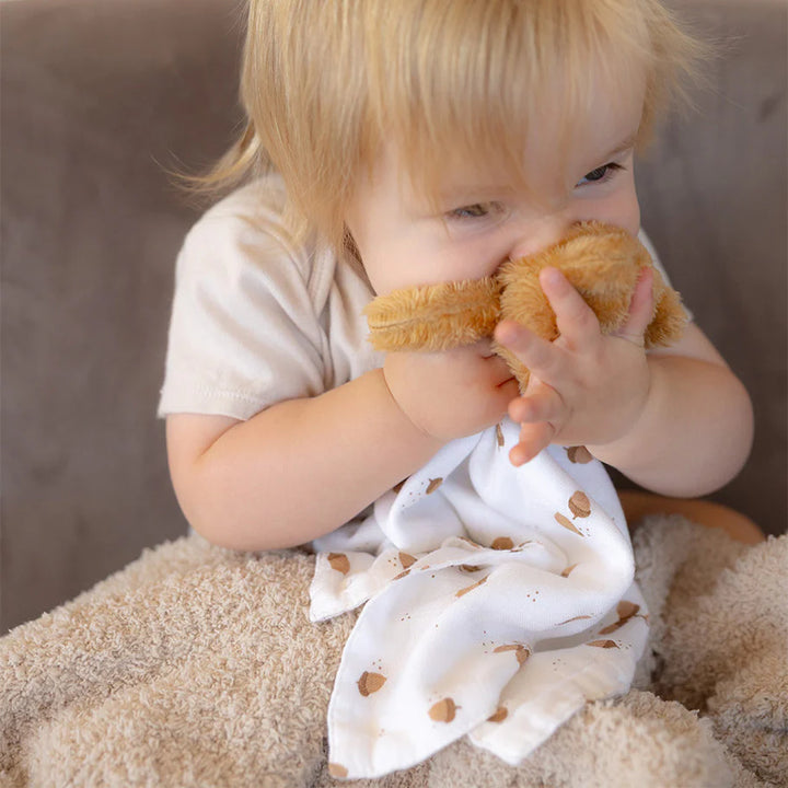 Child holding a plush toy with a neutral background
