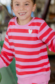 Child wearing a red and pink striped shirt with a heart design.