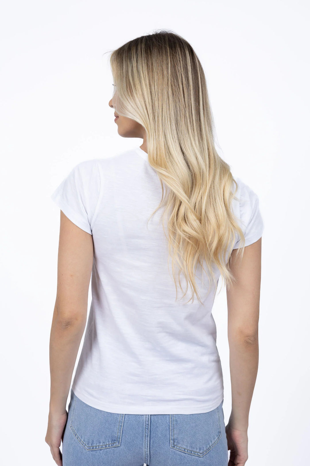 Woman wearing a plain white t-shirt and light blue jeans on a white background