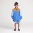Child wearing a blue and brown raincoat with striped shorts on a white background