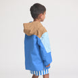 Child wearing a blue and brown jacket on a light gray background