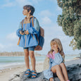 Two children on a beach with a clear blue sky and ocean.