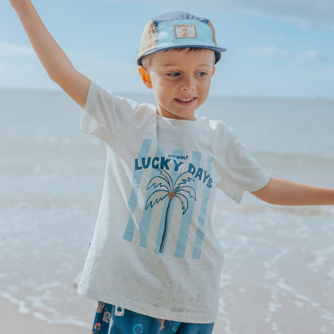 Child wearing a 'Lucky Days' Crywolf t-shirt on a beach