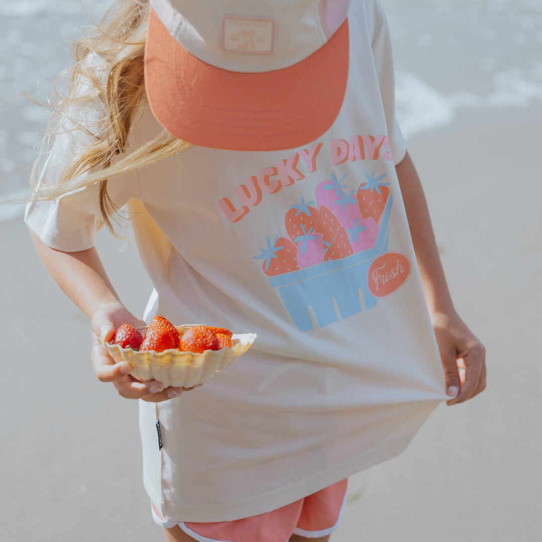 Person wearing a 'Lucky Dayz' CRYWOLF t-shirt holding a plate of strawberries.