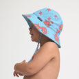 Child wearing a CRYWOLF blue sun hat with pink lobster pattern on a light gray background