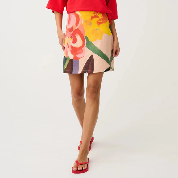 Woman wearing a red top and colorful floral skirt on a white background