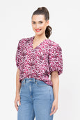Woman wearing a pink patterned blouse and blue jeans on a white background
