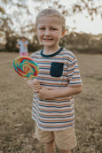 Young boy holding a large lollipop in an outdoor setting