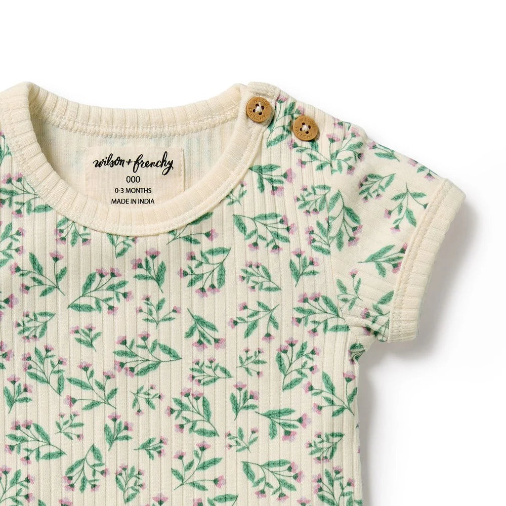 Baby romper with floral pattern and wooden buttons on a white background