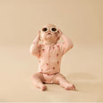 Baby wearing a pink Wilson & French strawberry-patterned onesie and sunglasses on a beige background