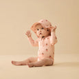 Wilson & Frenhcy Baby in pink outfit with matching hat on a beige background
