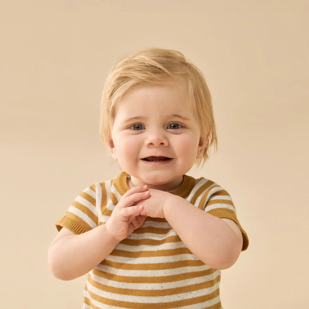 Child wearing a striped Wilson & frenchy shirt against a beige background