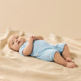 Baby in a blue Wilson & Frenchy outfit lying on a beige blanket