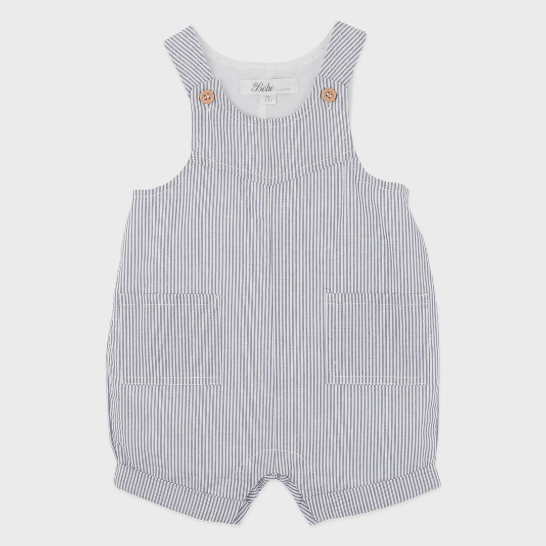 A baby romper with thin vertical navy and white stripes, featuring a white inner neck, decorative gold buttons on the shoulder straps, and two front patch pockets.