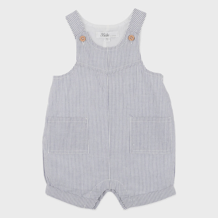 A baby romper with thin vertical navy and white stripes, featuring a white inner neck, decorative gold buttons on the shoulder straps, and two front patch pockets.