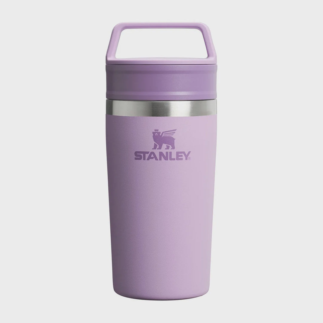 A lavender purple Stanley travel tumbler with a matching lid and carry handle, featuring a silver metallic band and the Stanley logo on the front, set against a light gray background.