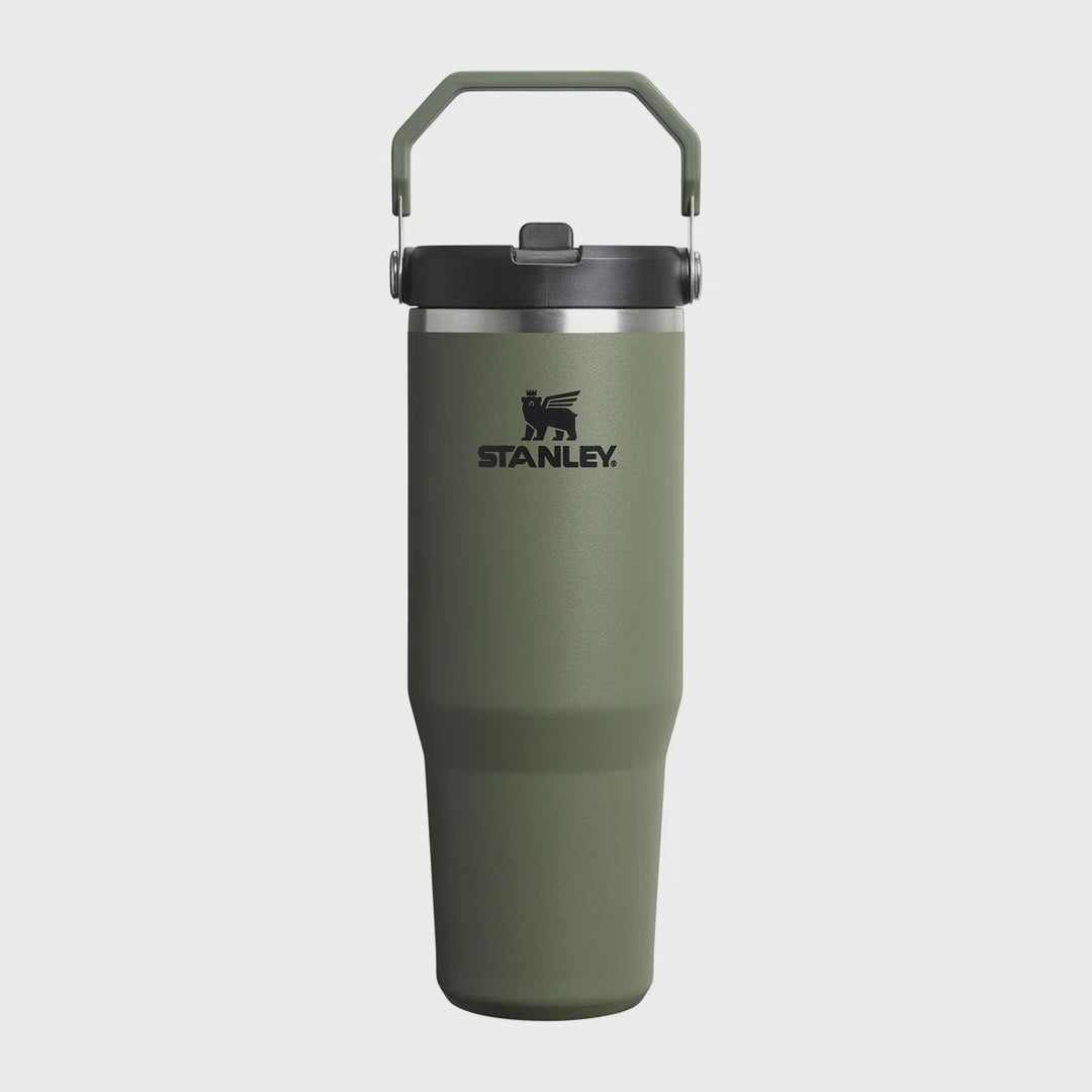 Stanley insulated travel tumbler in olive green with a dark gray lid and carrying handle, shown on a light gray background.