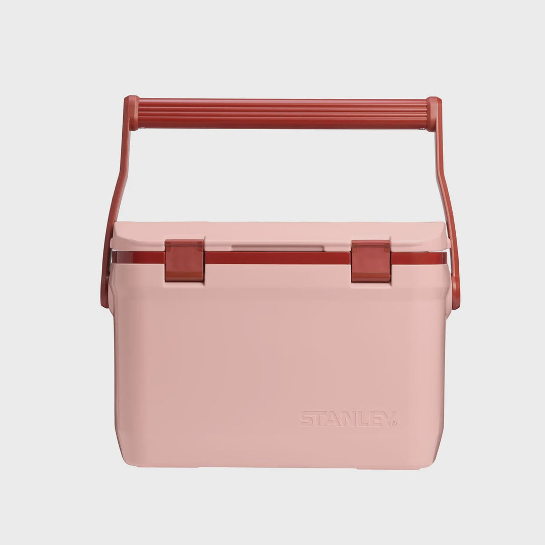 A light pink Stanley cooler with a terracotta red handle and latches, shown against a light gray background.