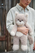 Child holding a fluffy teddy bear against a wooden background