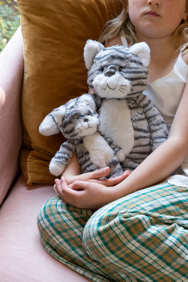 Child holding a plush cat toy on a couch