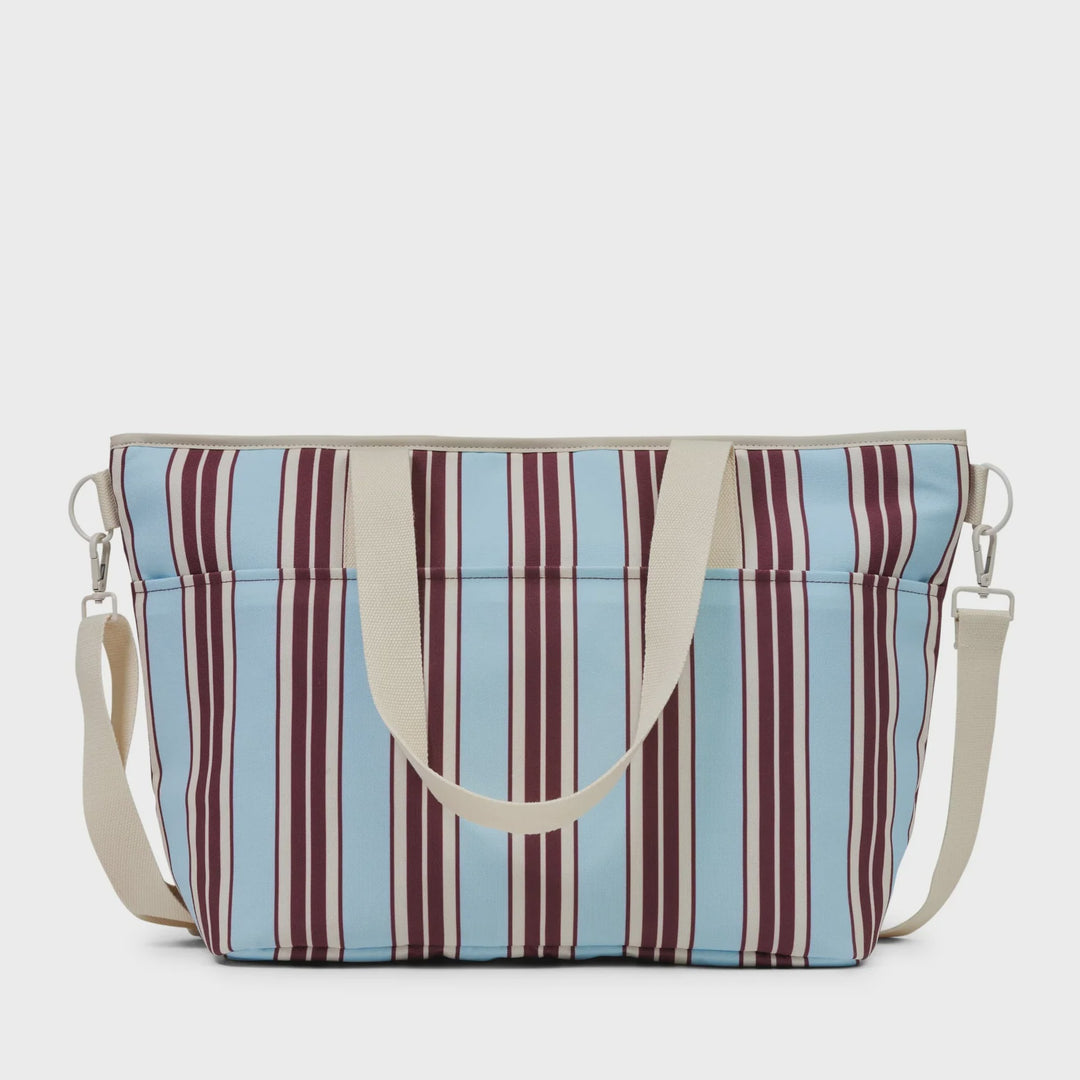 A striped tote bag with vertical light blue, beige, and burgundy stripes, featuring cream-colored handles and a matching detachable shoulder strap.