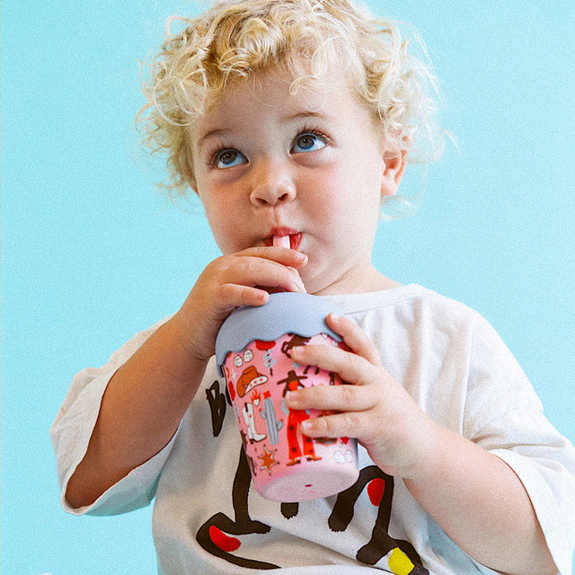 Child in pink sunglasses and swimsuit on a white inflatable pool float in clear blue water