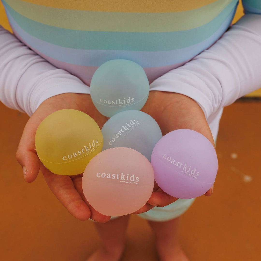 Pastel-colored stress balls with 'coastkids' branding held by a child.