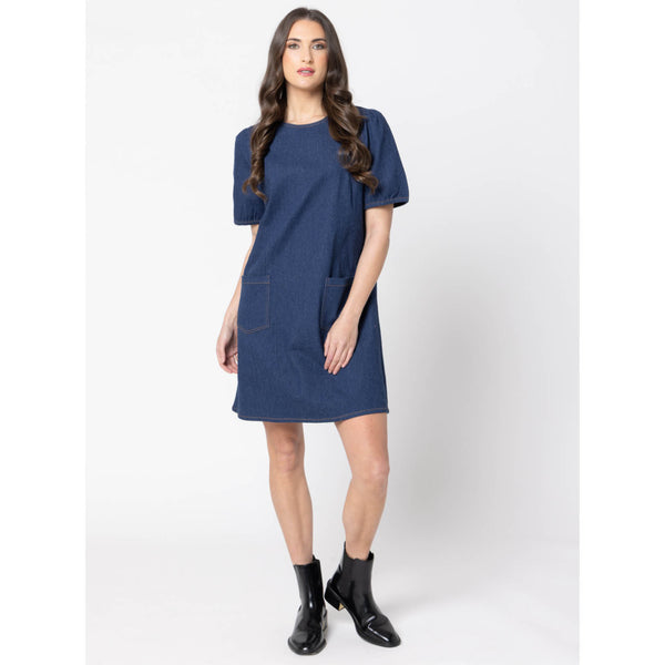 Woman wearing a blue drifter dress with black boots on a white background