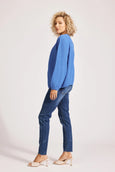 Woman wearing a blue eb & ive cardigan  and jeans on a white background