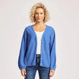 Woman wearing a eb & ive blue cardigan and jeans on a white background