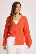Woman wearing a red eb & ive cardigan over a white top on a light background