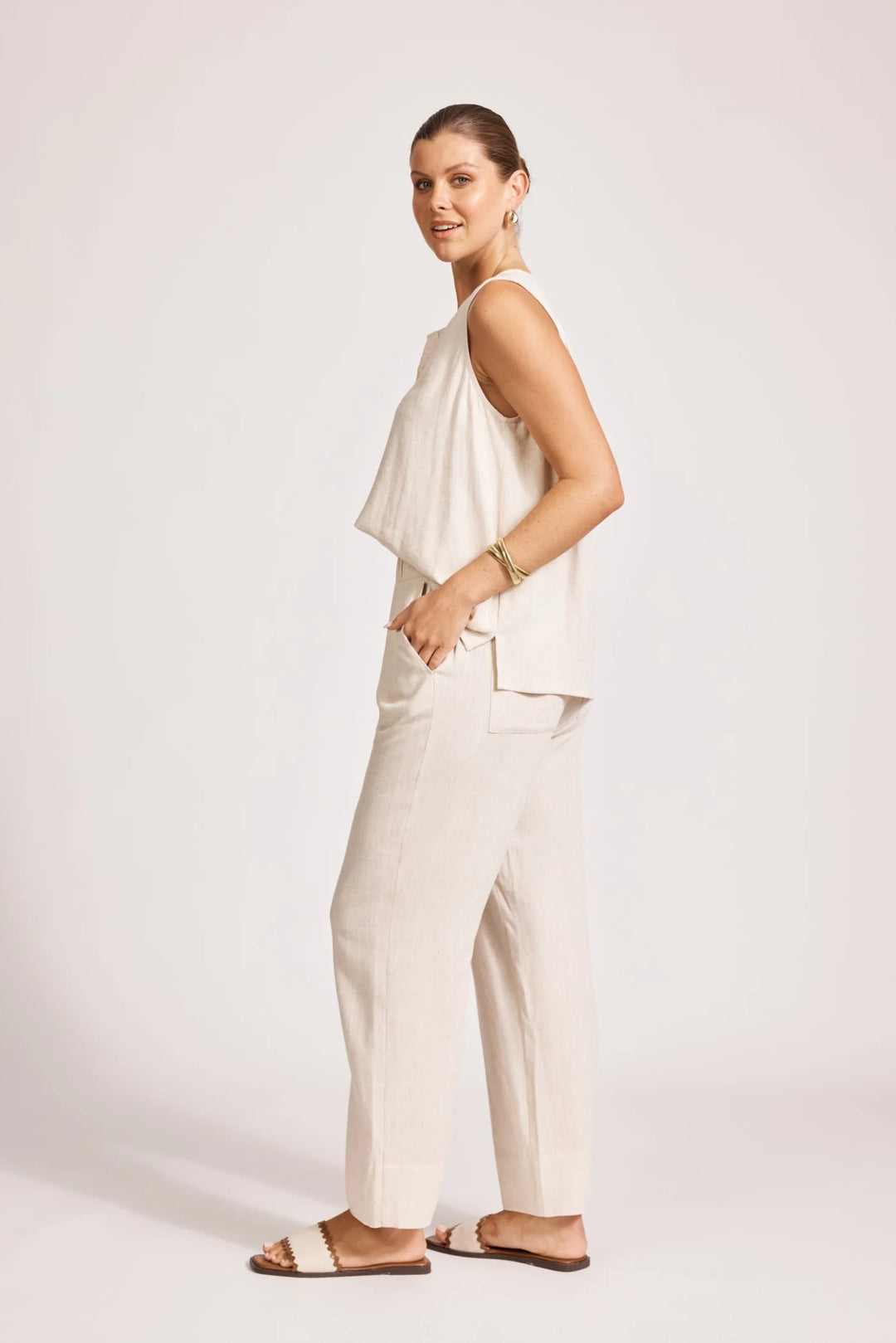 Woman wearing eb & ive white sleeveless top and beige pants on a white background
