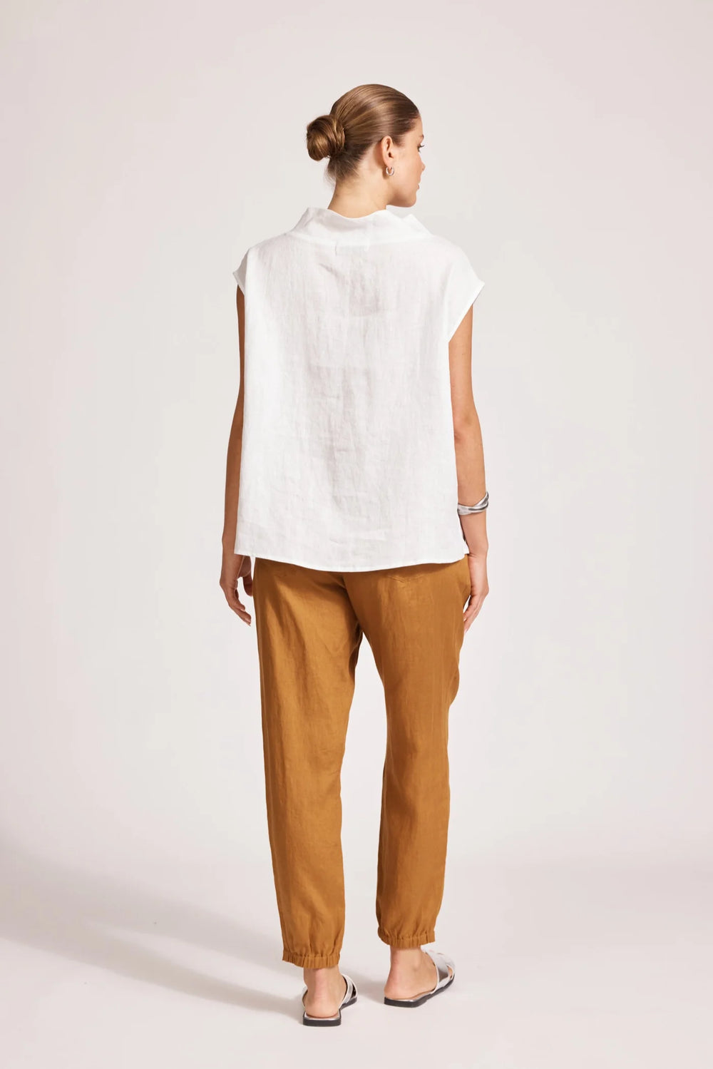 Woman wearing a eb & ive white top and brown pants on a plain background