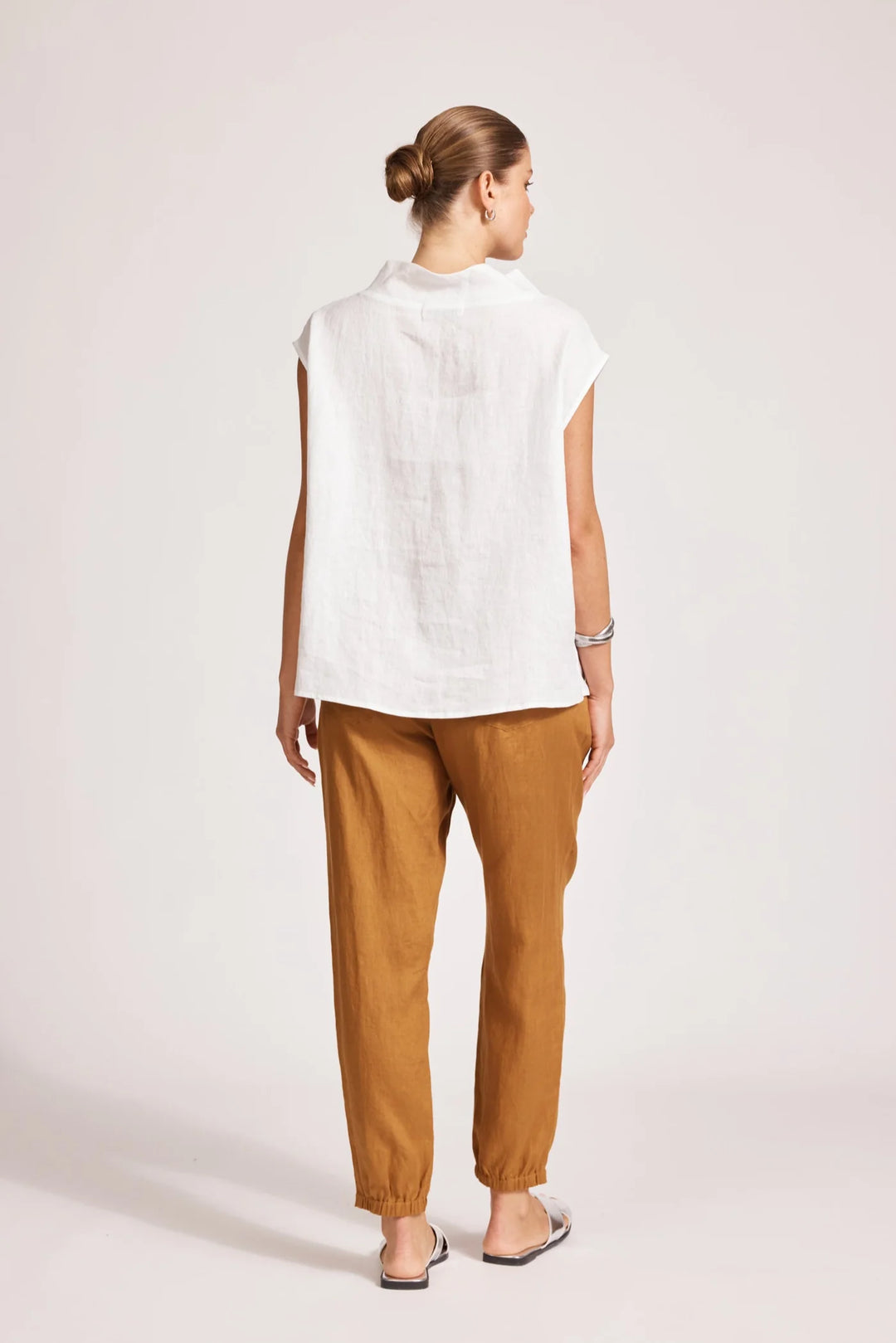 Woman wearing a eb & ive white top and brown pants on a plain background