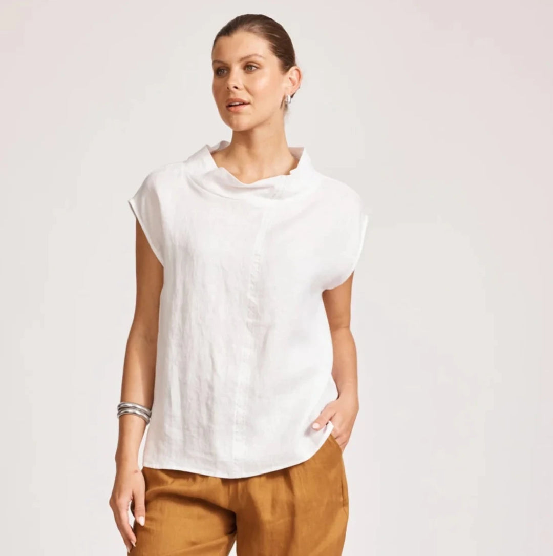 Woman wearing a eb & ive white top and brown pants on a plain background