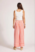 Woman wearing a white sleeveless top and eb & ive red and white striped pants on a light pink background