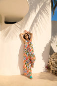 Woman in a colorful Haven outfit standing against a white wall with palm leaves.