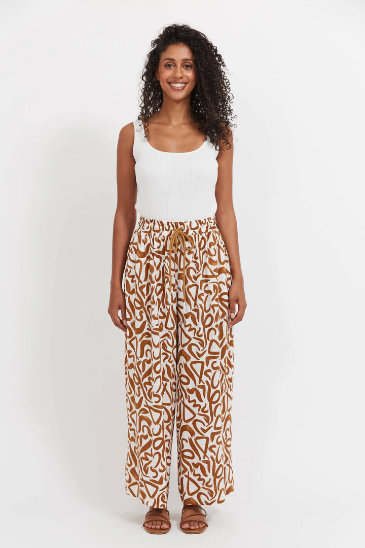 Woman wearing a white tank top and patterned Haven pants on a white background