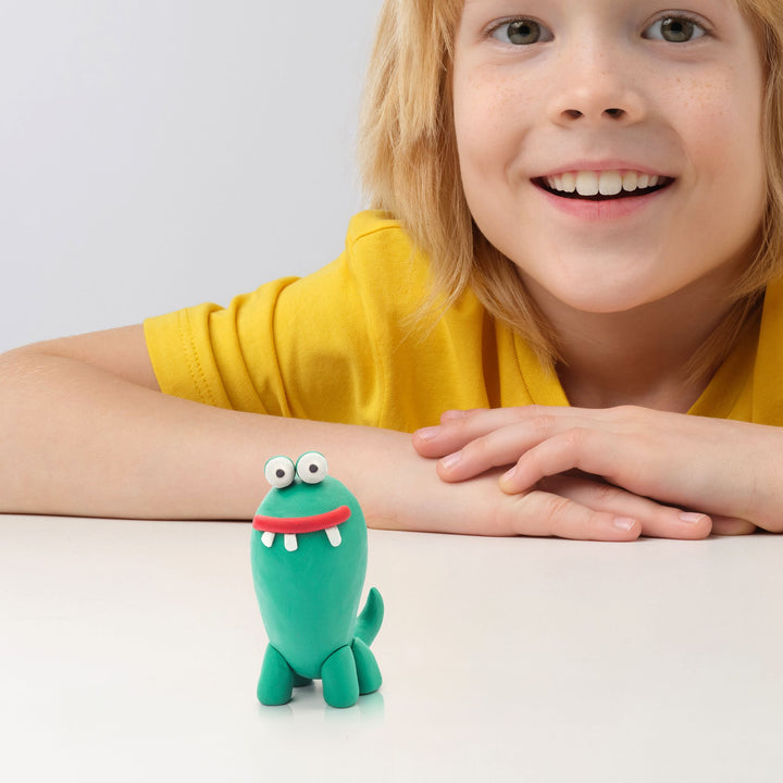 Child wearing a yellow shirt with a green toy on their wrist against a light background
