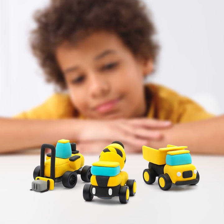 Child playing with toy construction vehicles on a white surface
