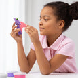 Young girl playing with a toy dinosaur and pink container on a white background