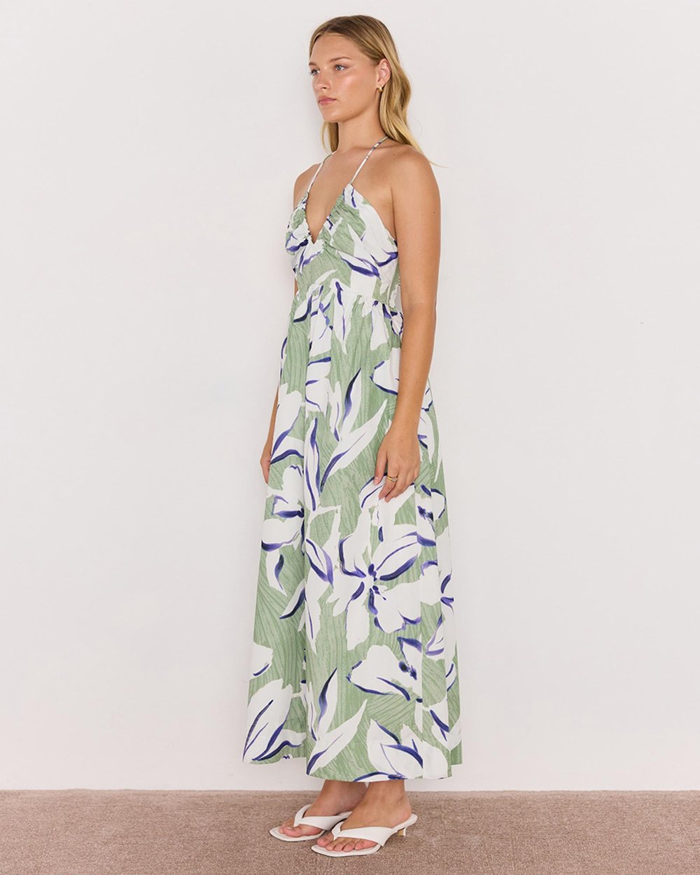 Woman wearing a green and white floral dress against a plain background